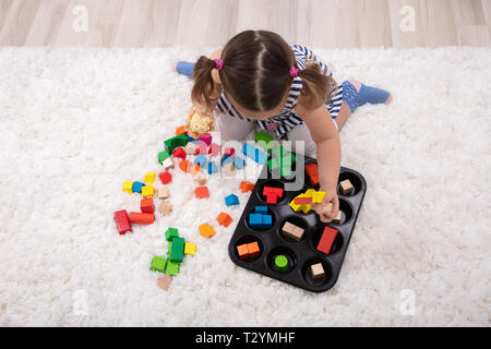 Ansicht von Mädchen sitzen auf dem Teppich Spielen mit bunten Bausteinen zu Hause Stockfoto