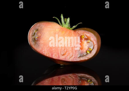 Die Hälfte der frischen Tomate primora auf schwarzem Glas isoliert Stockfoto