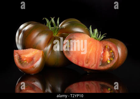 Gruppe von einer ganzen Hälfte eine Scheibe frischen Tomaten primora auf schwarzem Glas isoliert Stockfoto