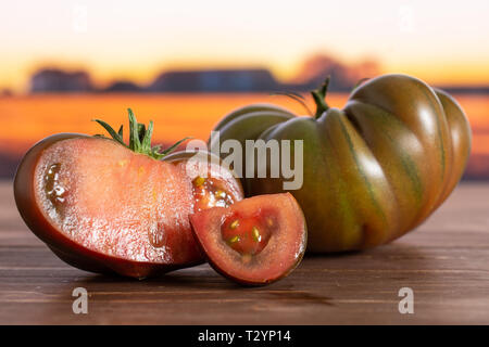 Gruppe von einer ganzen Hälfte eine Scheibe frischen Tomaten primora mit Herbst Feld im Hintergrund Stockfoto