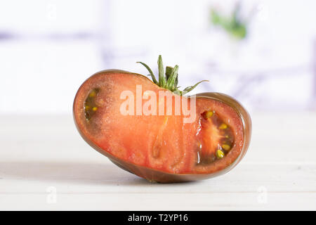 Die Hälfte der frischen Tomate primora in einem weißen Küche mit Blumen Stockfoto