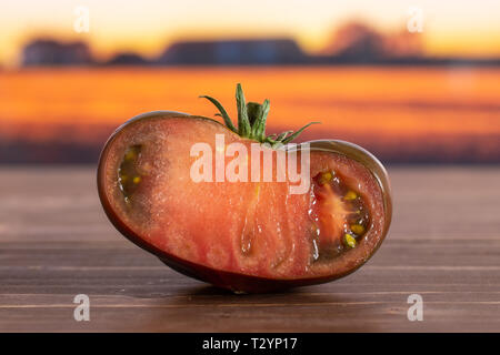 Die Hälfte der frischen Tomate primora mit Herbst Feld im Hintergrund Stockfoto