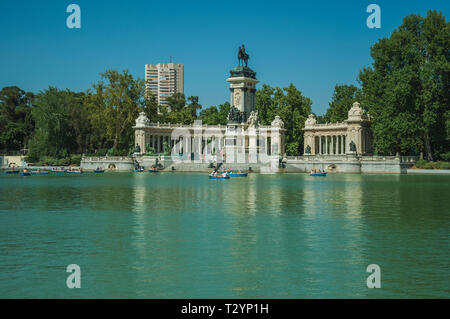 Menschen paddeln Boote auf dem reflektierenden Pool im Park El Retiro in Madrid. Hauptstadt von Spanien mit lebendigen und intensiven kulturellen Lebens. Stockfoto