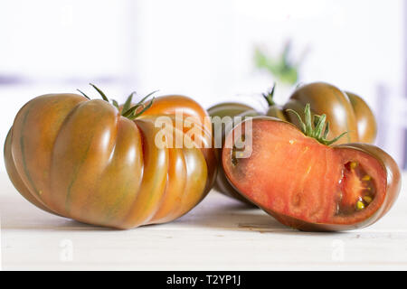 Gruppe von zwei ganze Hälfte der frischen Tomate primora in einem weißen Küche mit Blumen Stockfoto