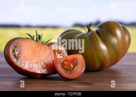Gruppe von einer ganzen Hälfte eine Scheibe frischen Tomaten primora mit grünen Weizenfeld Stockfoto