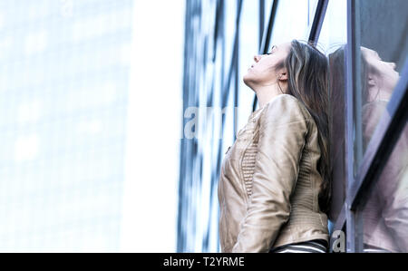 Gestresste, verärgerte, depressive und emotionale Frau. Traurige Person lehnt sich an das Gebäude. Ängstliche Dame allein in der Stadt. Burnout und Arbeitsdruck. Stockfoto