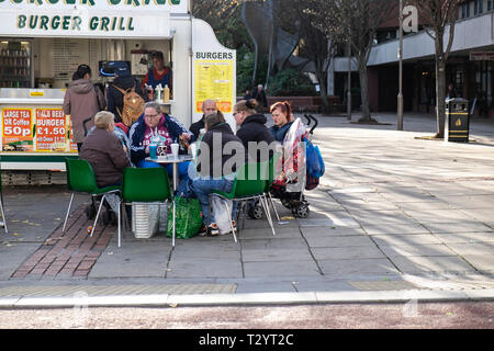 Familie Gruppe Essen sitzen um einen Tisch vor einem Burger Van auf dem Moor Fußgängerzone, Sheffield Stockfoto