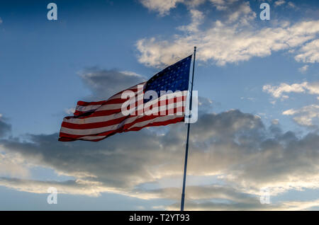 Die Flagge der Vereinigten Staaten von Amerika fliegen auf einer Stange in einem bewölkten Himmel. Freiheit Ring mit den Sternen und Streifen lassen. Stockfoto