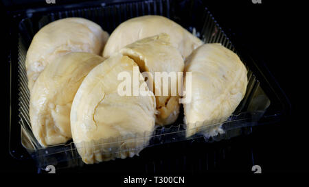 Nahaufnahme der geöffneten Plastikbehälter Verpackung mit großen gelben Durian König innen in Schwarz isoliert Stockfoto