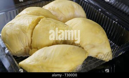 Nahaufnahme der geöffneten Plastikbehälter Verpackung mit großen gelben Durian König innen in Schwarz isoliert Stockfoto