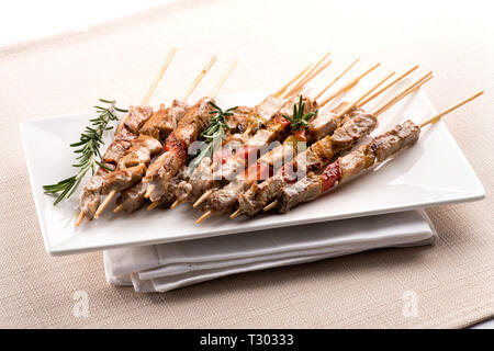 Arrosticini, oder Lamm am Spieß über einen canala Brazier gekocht, aus der Region Abruzzen Süditalien serviert auf einem Teller auf einem gefalteten Serviette Stockfoto