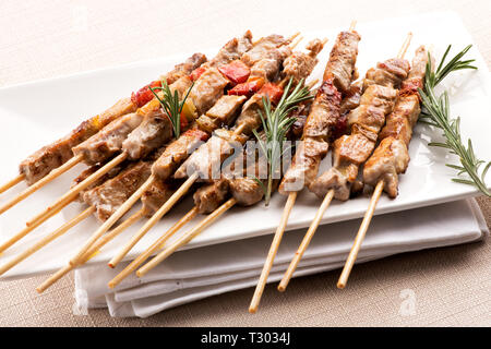 Herzhafte Marinade gewürzt arrosticini aus den Abruzzen, Italien von gegrillten kastriertes Lamm Fleisch oder Hammel auf einem Spieß mit frischen spr serviert mit Gewinde Stockfoto