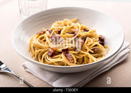 Spaghetti alla Carbanara aus dem Latium, Italien mit Ei, Käse, in der Regel Pecorino Romano, Pfeffer und guanciale oder kuriert Schweinefleisch in einer Schüssel am Tisch serviert Stockfoto