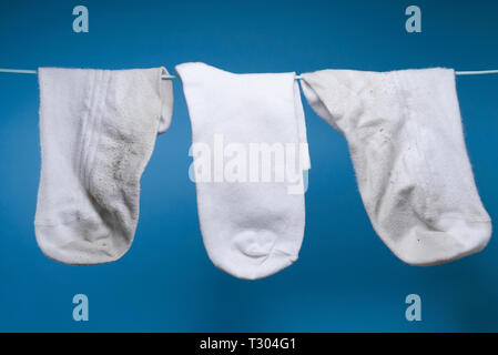 Zwei schmutzig weiß Alt und einer neuen, sauberen Socken wiegen auf dem Seil. blauen Hintergrund. Konzept der Wäsche, Reinigung Stockfoto