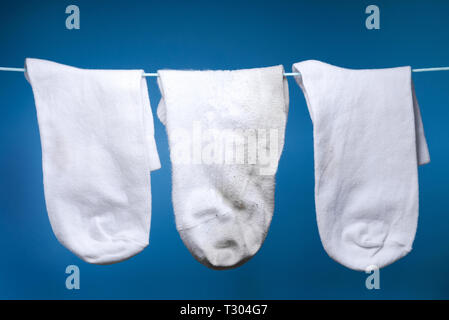 Eine alte und zwei neue, saubere Socke wiegen auf dem Seil. blauen Hintergrund. Konzept der Wäsche, Reinigung Stockfoto