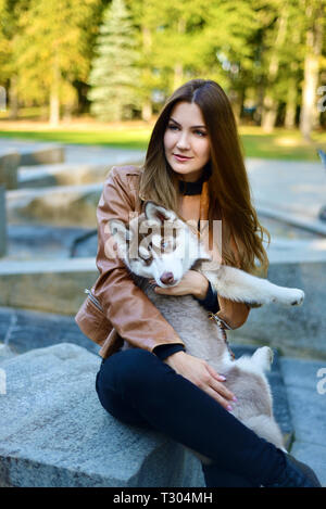 Schöne Mädchen, dass Hund. Husky Welpe lustig schaut weg Stockfoto