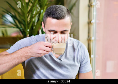 Der Mensch ist das trinken heißen Kaffee in einem Cafe mit Vergnügen Stockfoto