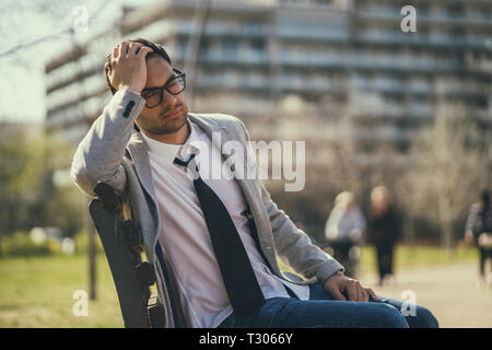 Junge müde Geschäftsmann ruht in der Park nach der Arbeit. Stockfoto