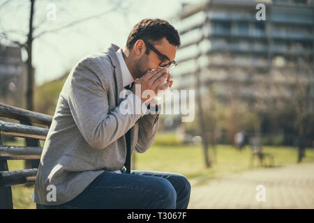 Junge Unternehmer ist die Allergie. Er bläst die Nase. Stockfoto