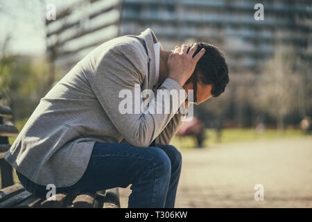 Junge Unternehmer ist sitzt im Park nach abgefeuert wurde. Er ist deprimiert. Stockfoto