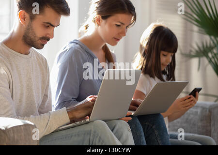 Familie sitzt auf der Couch in digitalen Geräten absorbiert Stockfoto