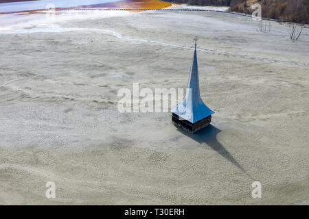 Antenne drone Ansicht der orthodoxen Kirche mit giftigen Abfall Wasser geflutet, Bergbau, chemische Rückstände, Schlamm. Ökologische Bombe, Geamana, Rumänien Stockfoto