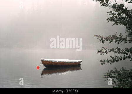 Ein Ruderboot auf der ruhigen See in den nebligen Herbst verankert. Stockfoto