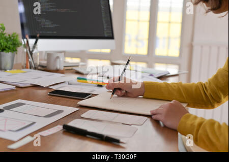 Eine weibliche Programmierer arbeiten mit Codierung auf Computer und Design ein reaktionsschnelles Website auf Papier. Stockfoto