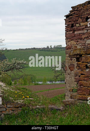 Die Ruinen einer alten Burg stand in einem Feld, auf denen wächst Frühling Gras und Blumen vor blauem Himmel Stockfoto