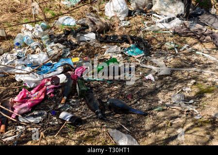 Abfälle aus Kunststoff und Glas Flaschen, Verpackungen und anderen Arten von Abfall auf illegalen Deponien im Park. Umweltverschmutzung Konzept Stockfoto