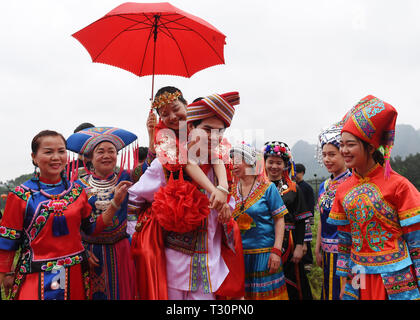 Du'an, China Guangxi Zhuang autonomen Region. 4 Apr, 2019. Ein "Bräutigam" hat die "Braut" auf seinem Rücken während einer Leistung der Hochzeit brauch der Zhuang ethnische Gruppe in Du' ein Yao autonomen County, South China Guangxi Zhuang autonomen Region, 4. April 2019. Credit: Lu Boan/Xinhua/Alamy leben Nachrichten Stockfoto