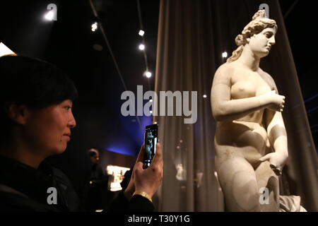 (190405) - Athen, April 5, 2019 (Xinhua) - ein Besucher nimmt Fotos auf einer Römischen Statue der griechischen Göttin Aphrodite, die zum ersten Mal an der Ausstellung ist "die zahlreichen Aspekte von Schönheit" durch das Nationale Archäologische Museum statt, in Athen, Griechenland, 4. April 2019. Eine Marmorstatue der griechischen Antike Göttin Aphrodite zusammen mit zwei Düfte aus der Antike wurden im Nationalen Archäologischen Museum von Griechenland am Donnerstag vorgestellt einjährigen Jahrestag der temporären Ausstellung "Die zahlreichen Aspekte von Schönheit zu markieren.' mit 'Feature: Aphrodite Statue auf Maiden anzuzeigen, Stockfoto