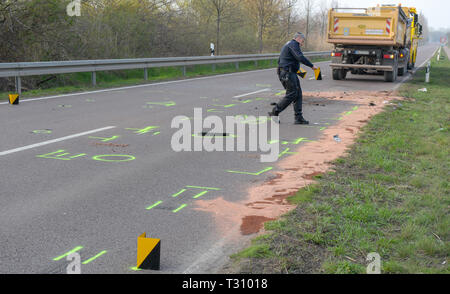 05 April 2019, Sachsen-Anhalt, Halle (Saale): Nach einem Unfall wird ein Lkw auf der Straße zwischen Halle und Sennewitz, während ein Polizist an der Unfallstelle die Beweise untersucht und Beweissicherung. Eine Frau war mit ihrem Auto auf die Gegenfahrbahn und kollidierte mit einem entgegenkommenden Fahrzeug. Der Fahrer starb noch an der Unfallstelle und einer anderen Person wurde schwer verletzt. Die Polizei ist nicht in der Lage, die Ursache des Unfalls zu ermitteln. Foto: Heiko Rebsch/dpa Stockfoto