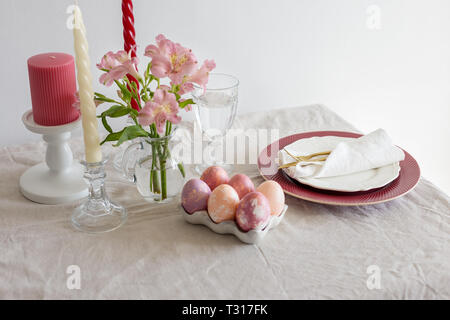 Festliche Ostern Frühling Tischdekoration mit Blumen, Kerzen und Geschirr auf Leinen Tischdecke in den hellen Tag. Konzept der Ostern Mahlzeit, freie Platz für Text Stockfoto