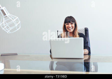 Porträt eines lächelnden Frau Unternehmer an Ihrem Schreibtisch im Büro Arbeiten am Laptop. Im Büro Geschäftsfrau Arbeiten am Laptop. Stockfoto