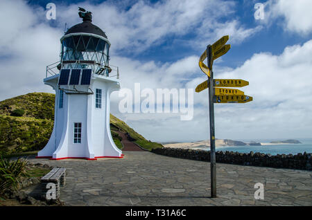 Leuchtturm view mit Wegweiser von Cape Reinga mit blauem Himmel und weißen Wolken über, Northland, Neuseeland. Stockfoto