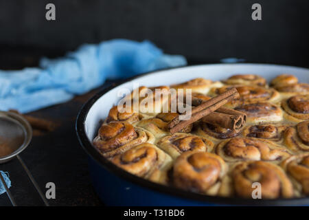 Cinnamon Roll Tarte mit Zuckersirup in vintage Backblech auf schwarzem Hintergrund Stockfoto