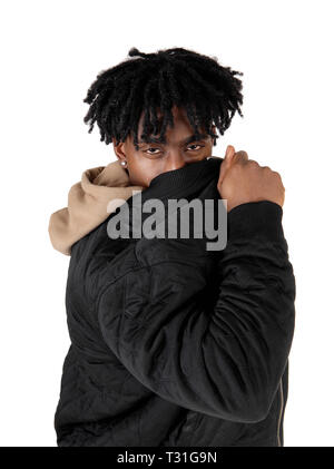 Eine afrikanische amerikanische Mann im Studio sein Gesicht hinter seine Jacke in die Kamera schaut, auf weißem Hintergrund Stockfoto