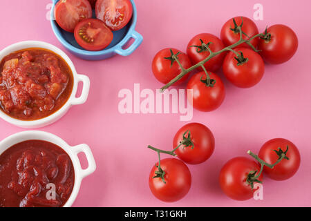 TopView von roten Tomaten, Ketchup und Bruschetta in rosa Hintergrund Stockfoto