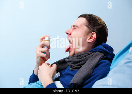 Foto von der Seite der Kranken Schal mit Spray mit Medizin für Hals im Bett liegend Stockfoto