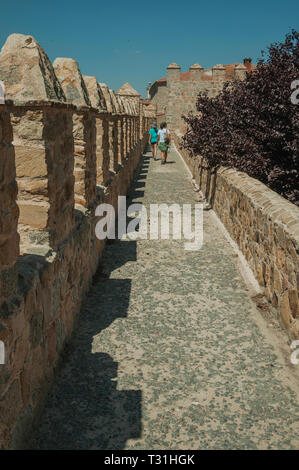 Menschen zu Fuß auf Weg über Stein dicke Wand mit grünen Baum in Avila. Mit einer imposanten Mauer rund um die gotische Stadt Zentrum in Spanien. Stockfoto