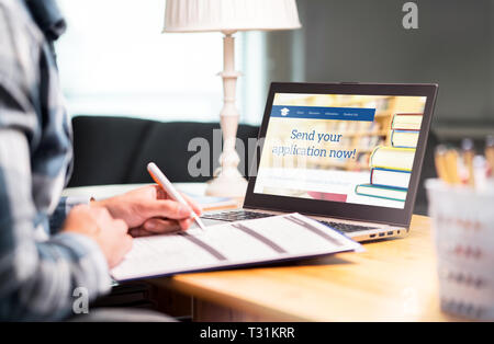 Junger Mann, der ein College- oder Universitätsanfrageformular mit Stift und Papier schreibt. Student beantragt oder füllt Dokument aus. Stipendien, Zuschüsse oder Eintritt. Stockfoto