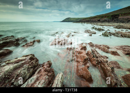 Felsen im Meer bei Manorbier, Pembrokeshire, Wales, auf eine lange Belichtung Stockfoto