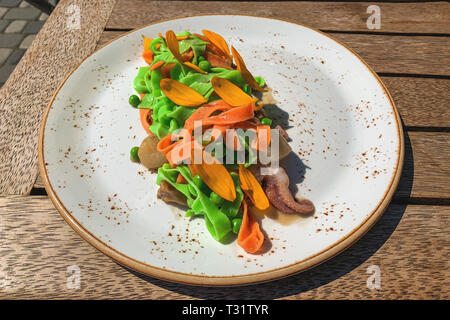 Italienisch bunte Nudeln mit Meeresfrüchten - Jakobsmuschel, Garnelen und Tintenfisch fangarme. Mit Gelben daisy Blüten dekoriert. Schöne und originelle Gerichte Stockfoto