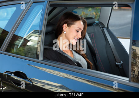 Seitenansicht des lächelnden Jungen Geschäftsfrau, Sitzen im Auto. Stockfoto