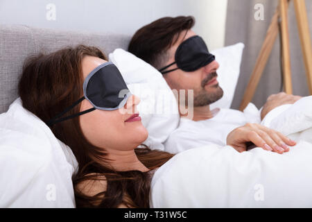 Junges Paar schlafend auf dem Bett mit Augenmaske im Schlafzimmer Stockfoto