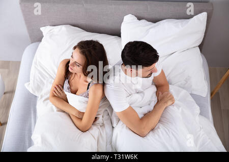 Blick von oben auf die verzweifelten Ehepaar Rücken an Rücken auf dem Bett Stockfoto