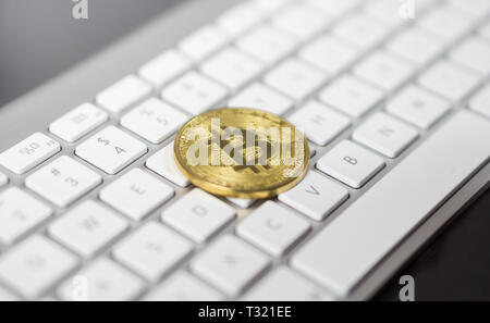 Foto von Cyptocurrency golden Bitcoin zur Festlegung auf weiße Tastatur im Hintergrund. Symbol der elektronischen virtuelles Geld. Stockfoto