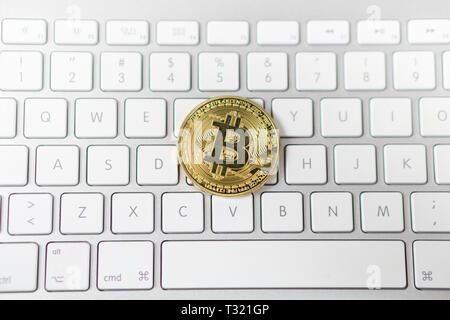 Foto von Cyptocurrency golden Bitcoin zur Festlegung auf weiße Tastatur im Hintergrund. Symbol der elektronischen virtuelles Geld. Stockfoto