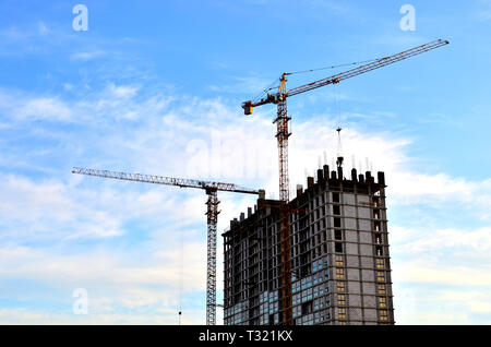 Industrielle Baukräne und Silhouetten von Arbeitnehmern während der Installation von Schalung und Beton Stockfoto